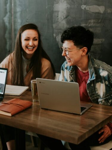 three people sitting in front of table laughing together